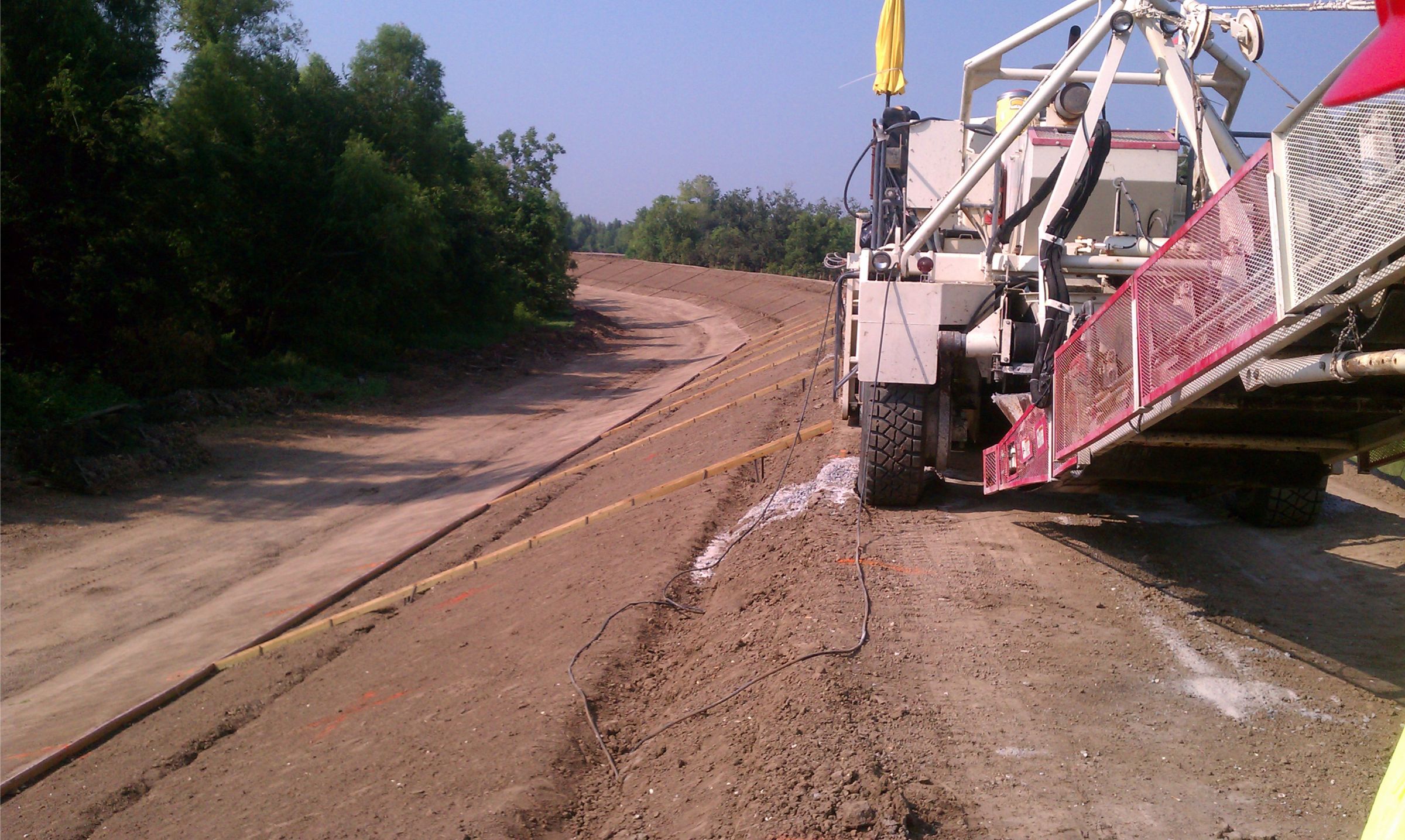Heavy machinery paving a levee.